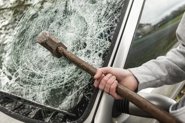 A sledge hammer embedded in a car windscreen.